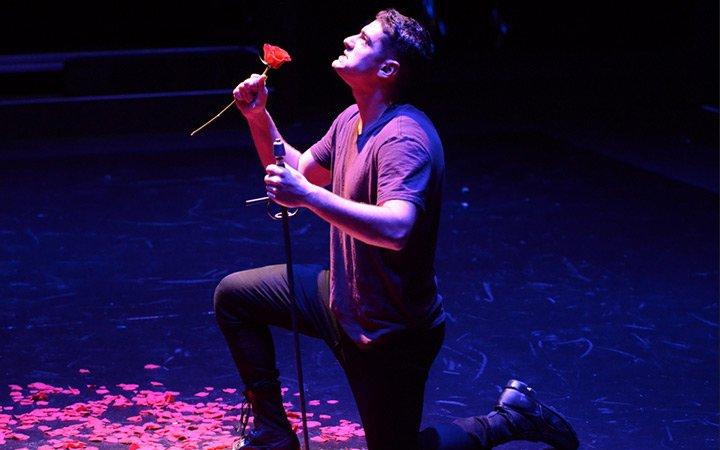 Male music theatre student kneeling during performance 